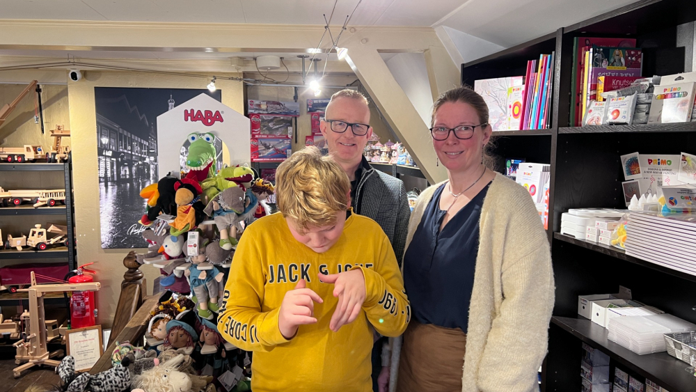 Drie mensen staan in een winkel met knuffels.